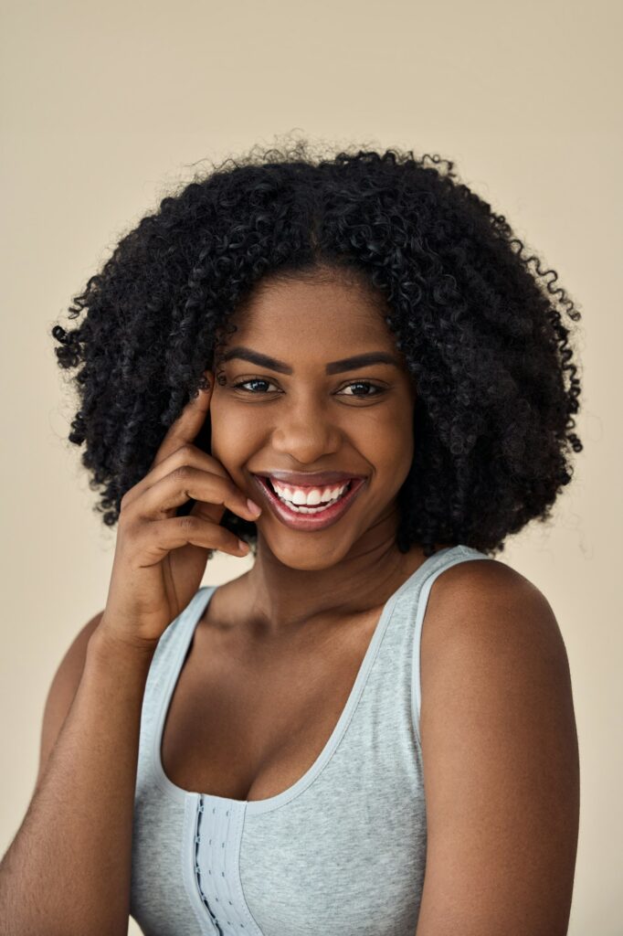 Happy young African American woman beauty model at beige background. Portrait.